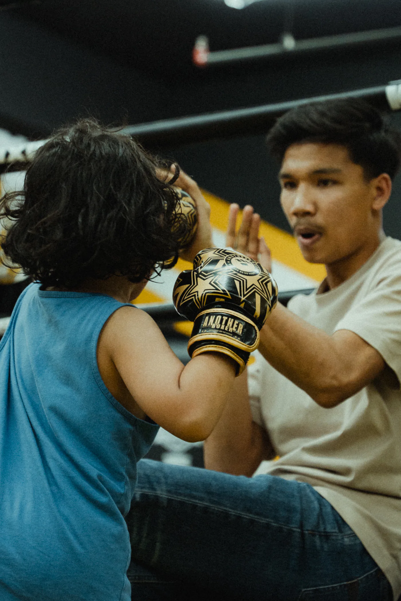 A KIB coach guiding a young boxer through pad work